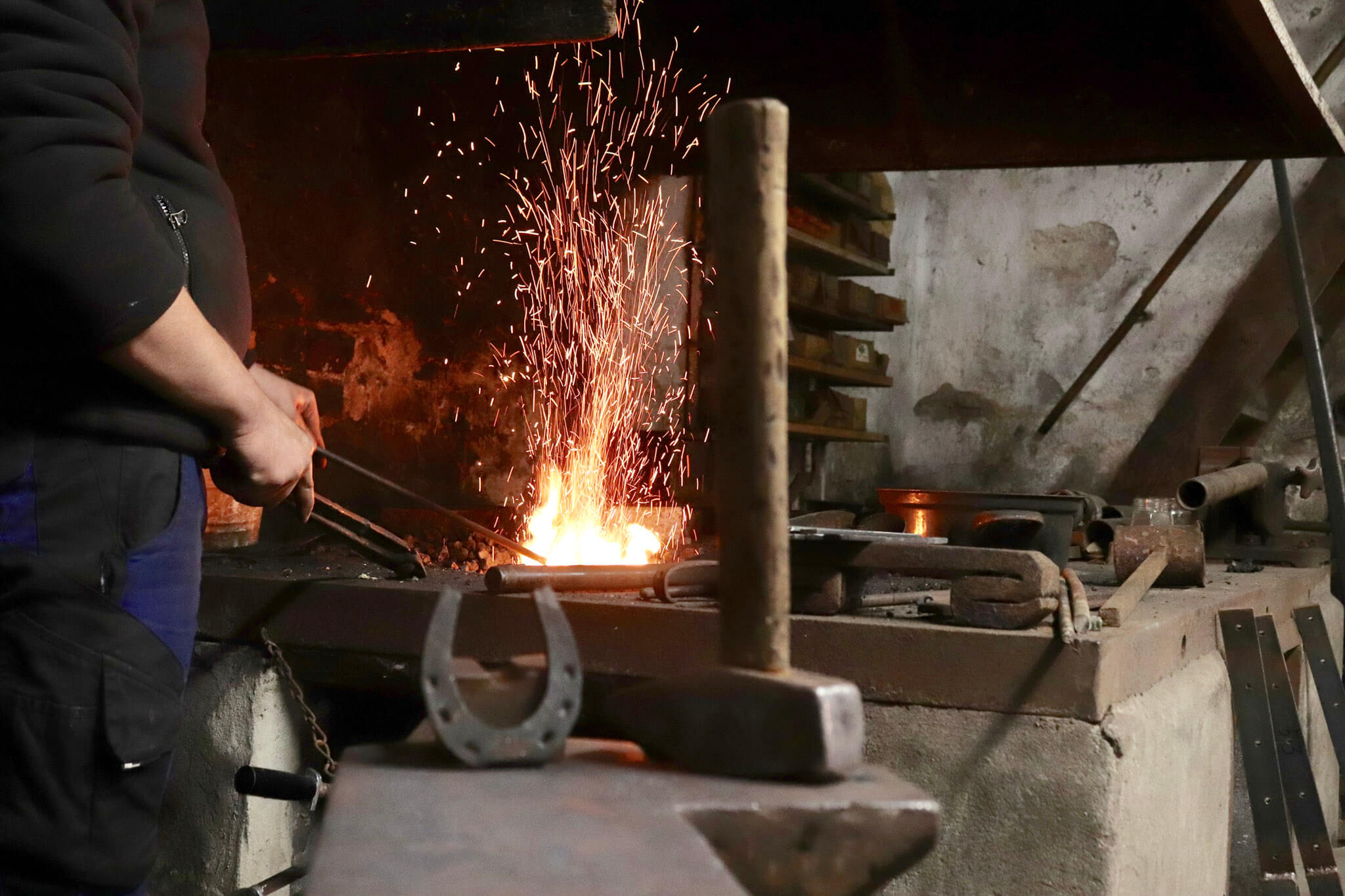 Schmiedewerkstatt wo ein Schmied gerade arbeitet und ein Hufeisen ist im Vordergrund