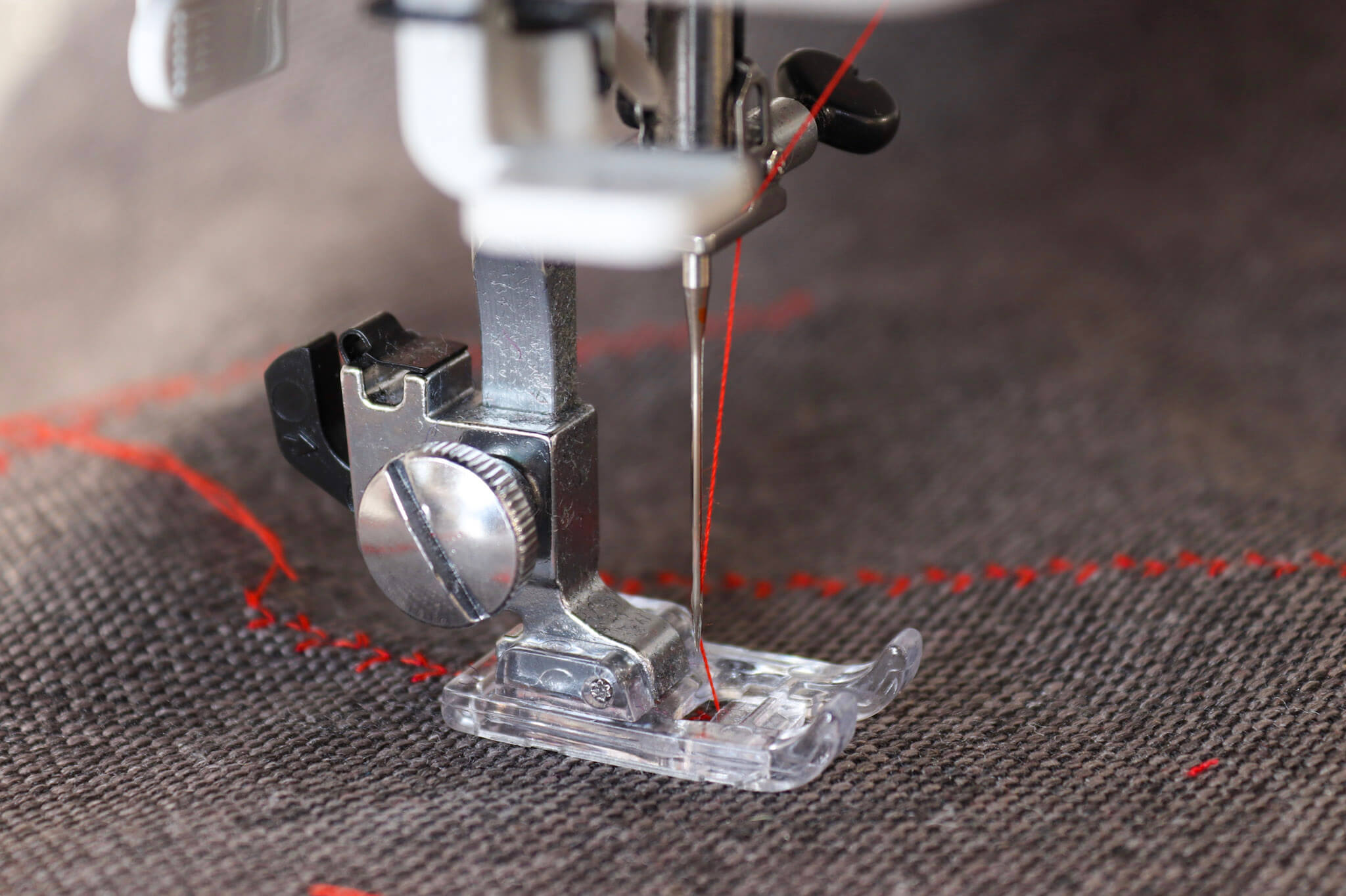 Nahaufnahme einer Nähmaschine welche auf Stoff näht.