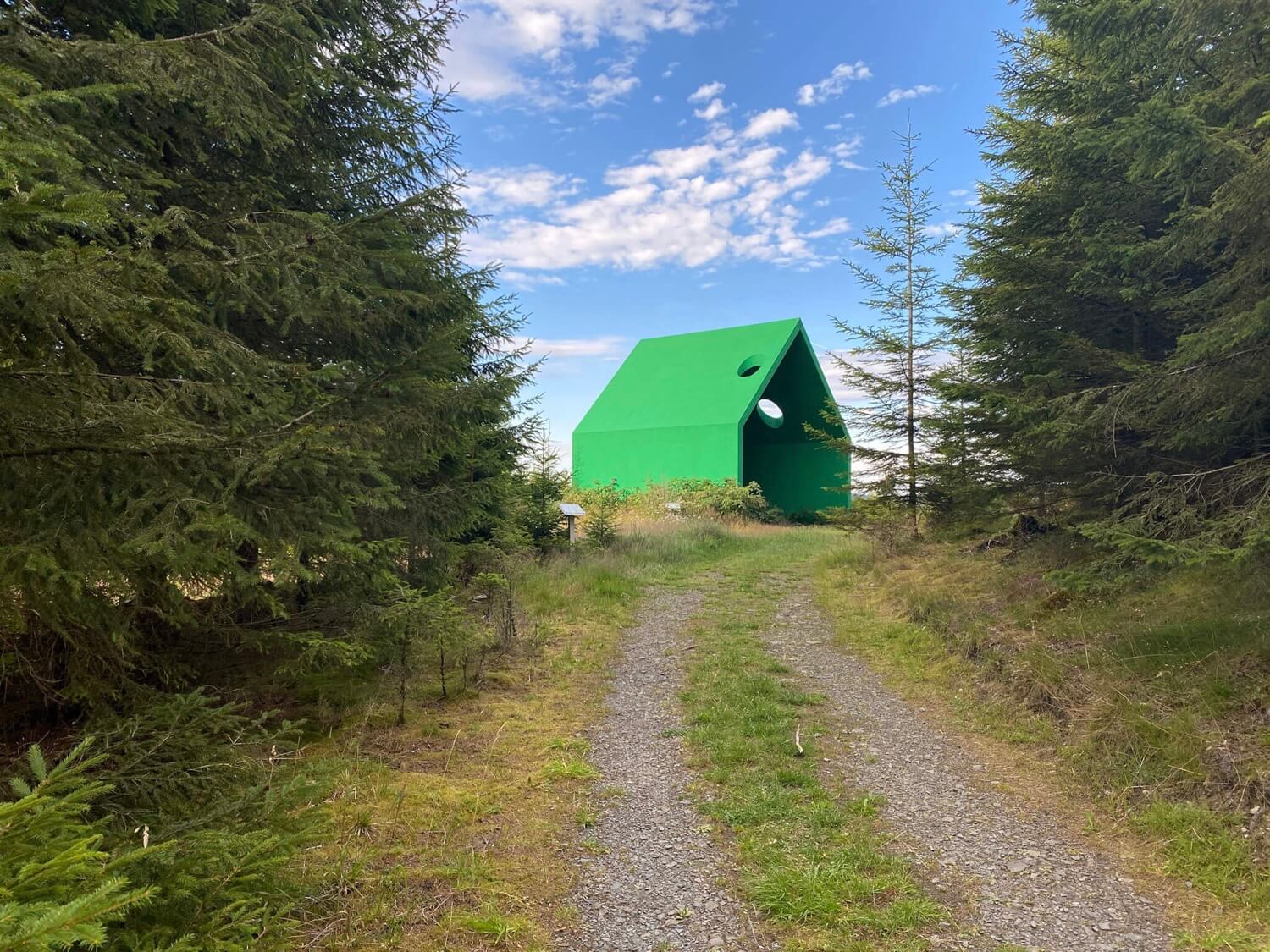 Ein Wanderweg führt auf ein grünes Haus zu.